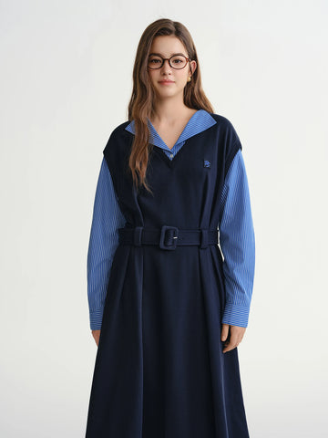 Woman wearing a navy dress with a blue shirt underneath on a white background