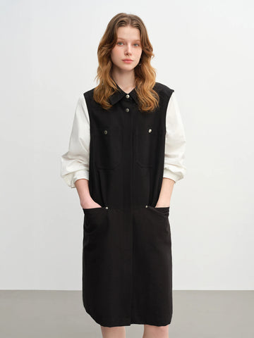 Woman wearing a black dress over a white shirt on a plain background