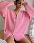 Woman wearing a pink ribbed cardigan with buttons indoors.