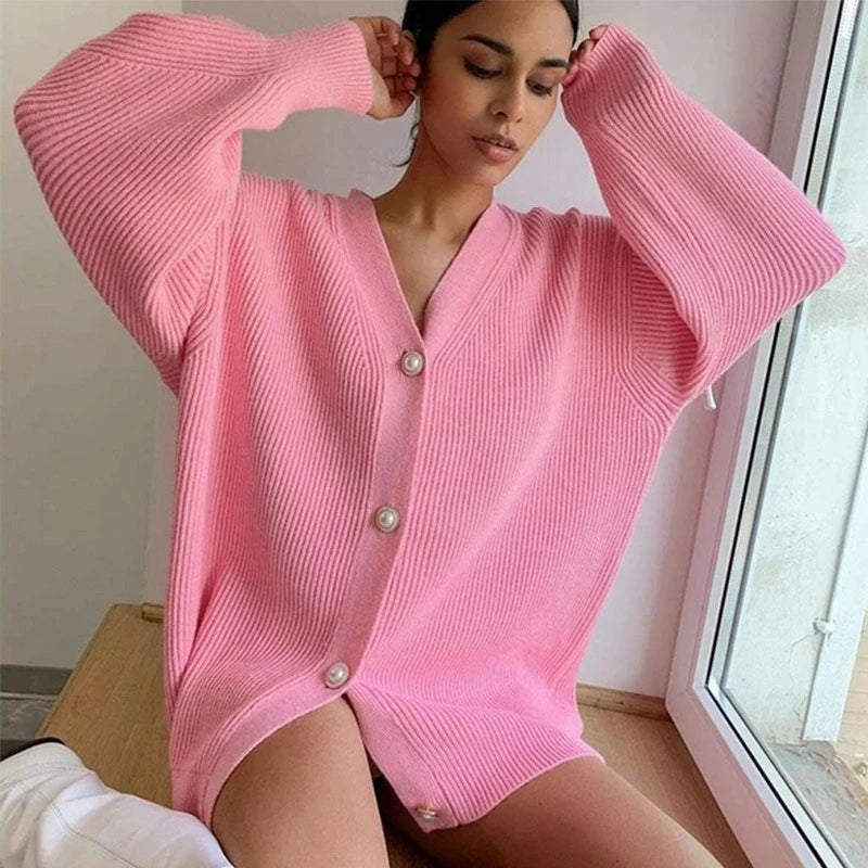Woman wearing a pink ribbed cardigan with buttons indoors.