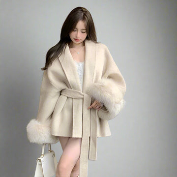 Woman wearing a beige coat with fur trim in an indoor setting