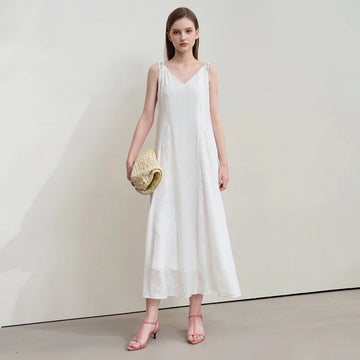 Woman wearing a white dress with a plain background, featuring the brand 'Amii'.