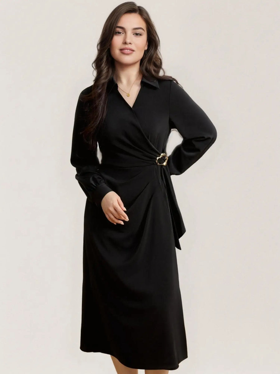 Woman wearing a black dress with a belt on a plain background