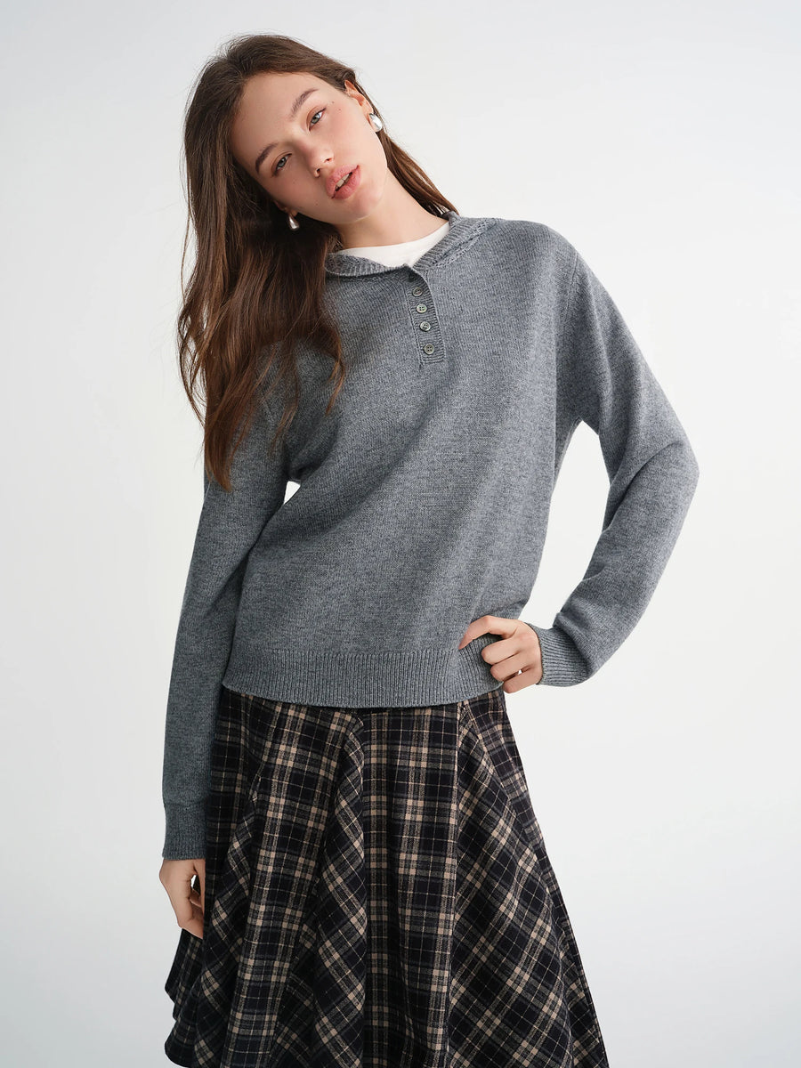 Woman wearing a gray sweater and plaid skirt on a white background
