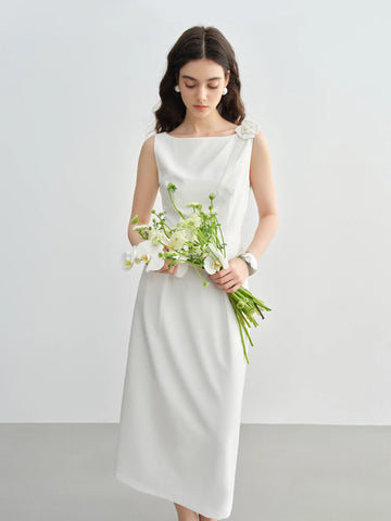 Woman in a white dress holding a bouquet of flowers against a plain background