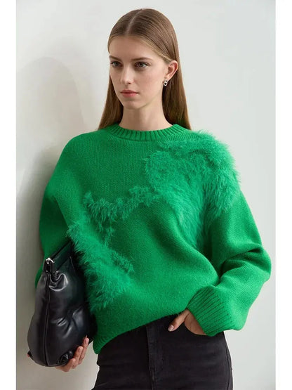 Woman wearing a green sweater holding a black bag against a light background