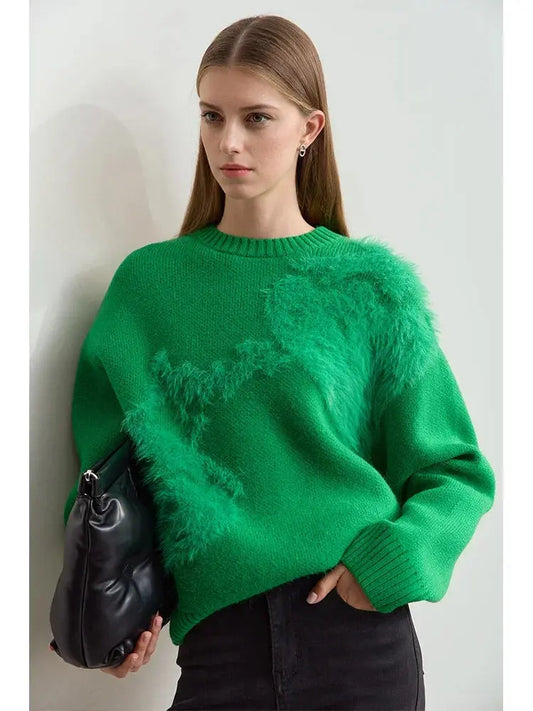 Woman wearing a green sweater holding a black bag against a light background