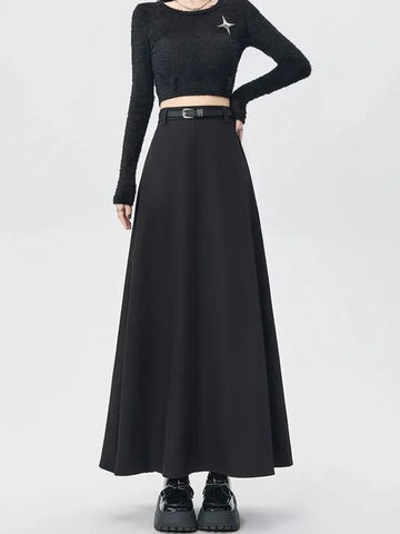 Person wearing a black long-sleeve crop top and black skirt on a white background