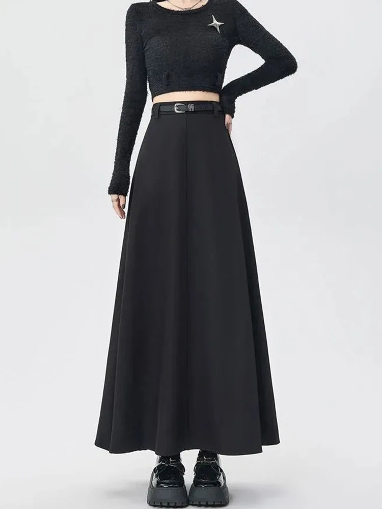 Person wearing a black long-sleeve crop top and black skirt on a white background