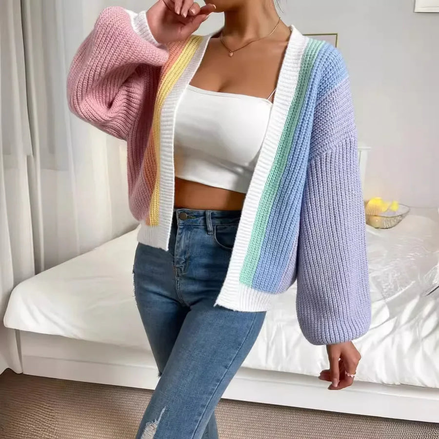 Person wearing a colorful cardigan over a white top and blue jeans in a bedroom setting.