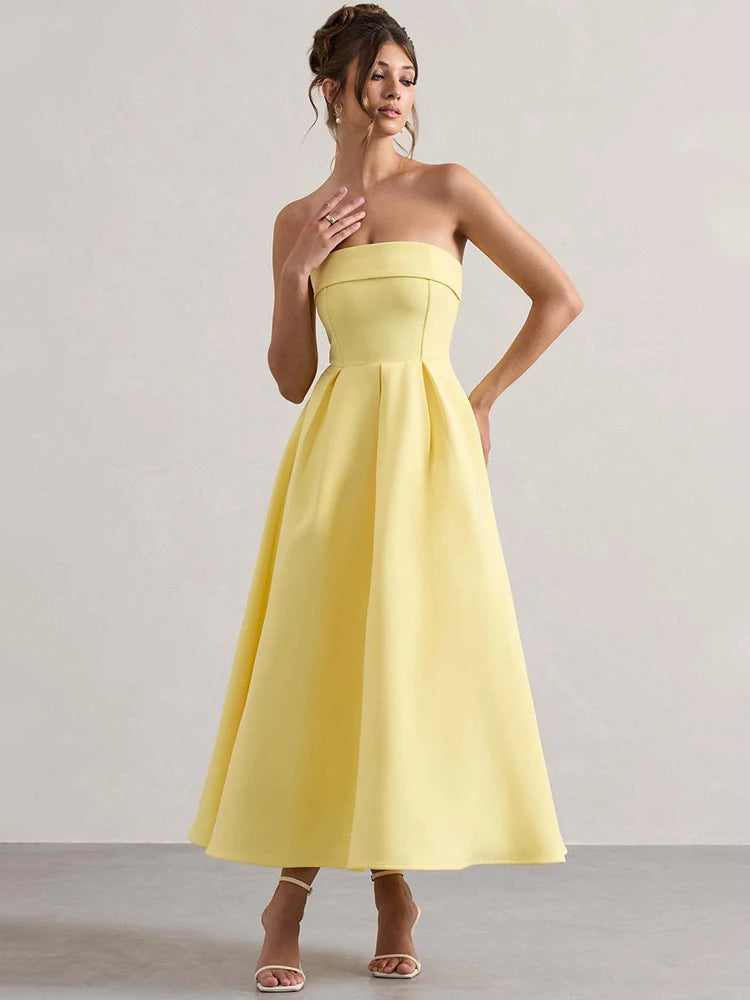 Woman wearing a yellow strapless dress against a plain background