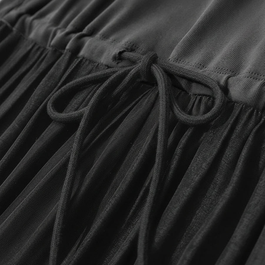 Close-up of a black dress with a drawstring detail, featuring the brand 'Amii'.