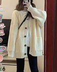 Person wearing a white cardigan taking a mirror selfie.