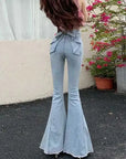 Light blue flared jeans worn by a person with flowers in the background