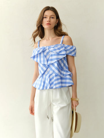 Woman wearing a blue and white striped top with ruffled layers on a plain background