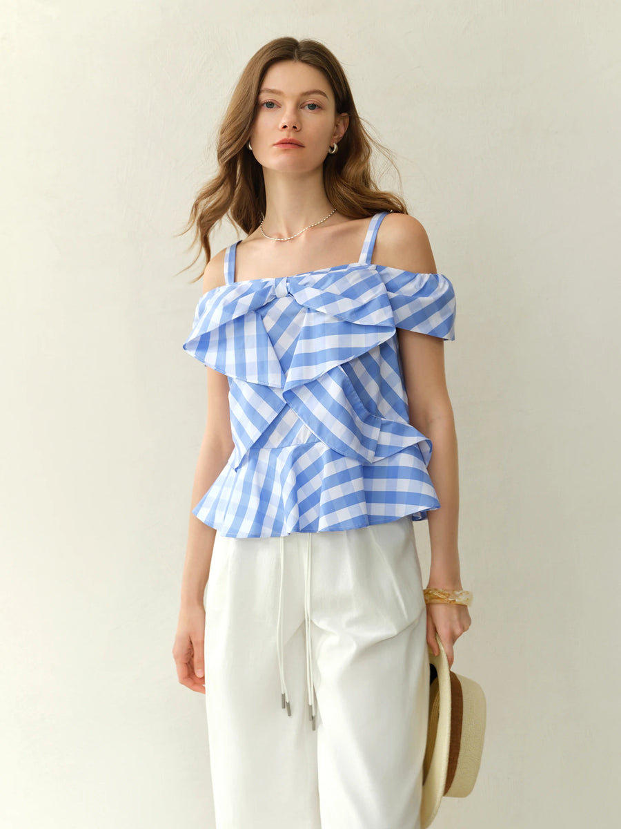 Woman wearing a blue and white striped top with ruffled layers on a plain background