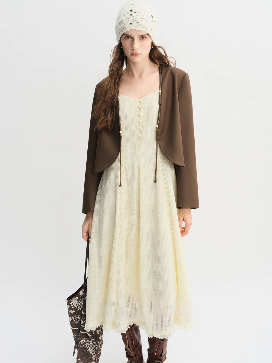 Woman wearing a brown jacket, white dress with lace details, and brown boots on a white background