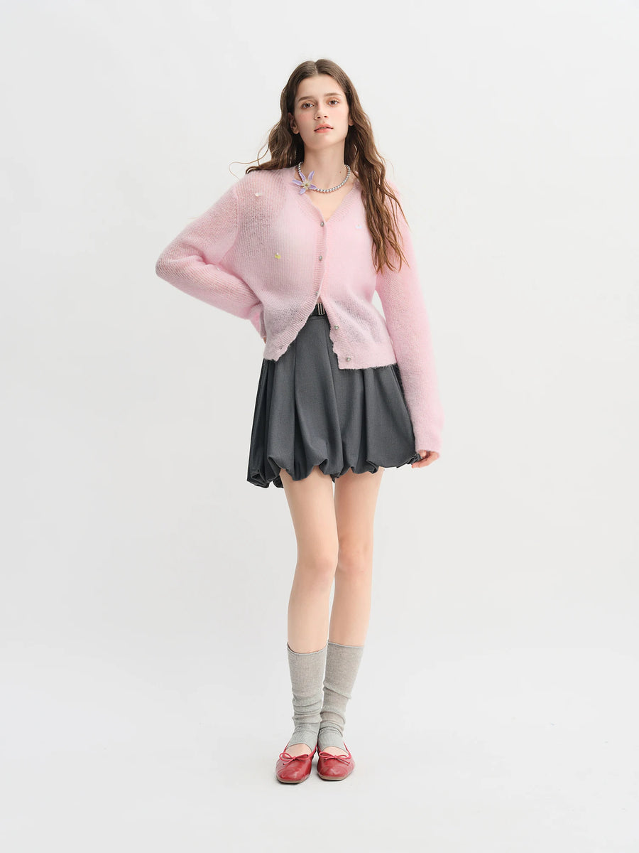 Woman wearing a pink sweater, gray skirt, and red shoes on a white background