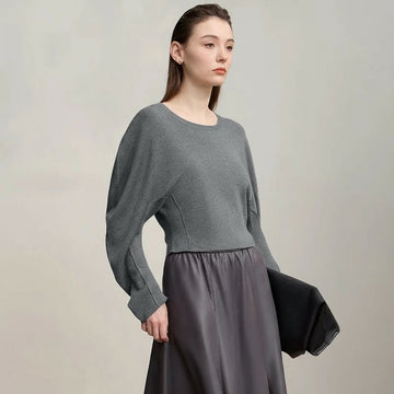 Woman wearing a gray sweater and skirt with 'Amii' brand logo.