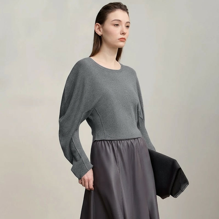 Woman wearing a gray sweater and skirt with 'Amii' brand logo.