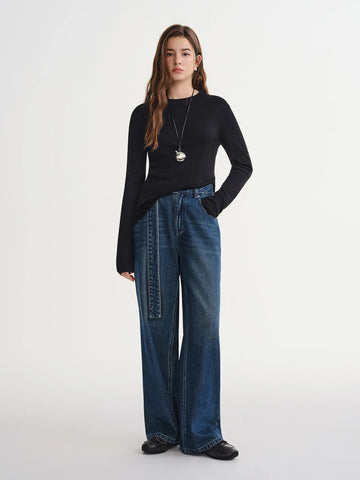 Woman wearing a black sweater and blue jeans on a white background