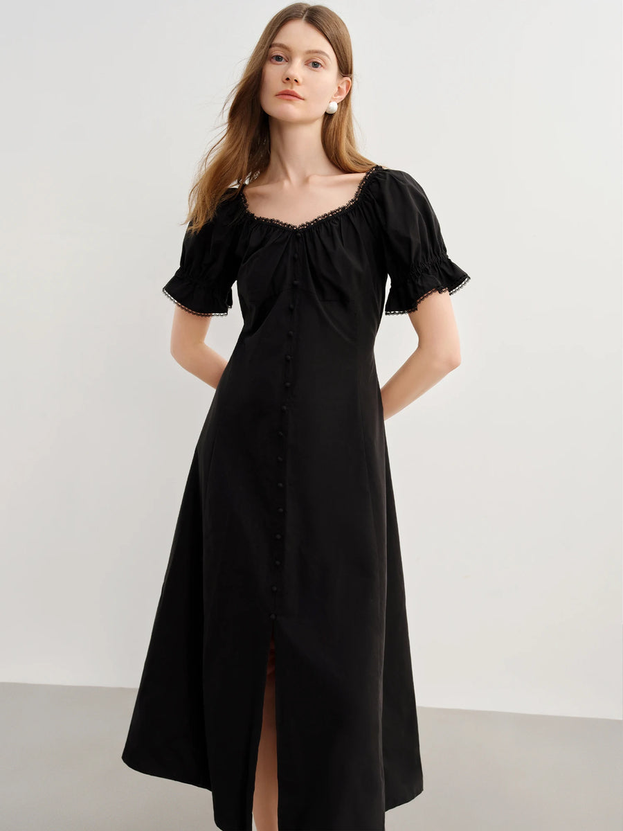 Woman wearing a black dress with short sleeves and a high slit on a white background