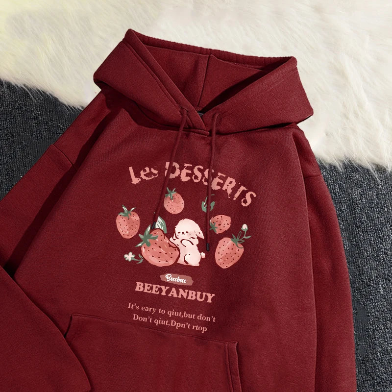 Maroon hoodie with strawberry design and text on a textured surface