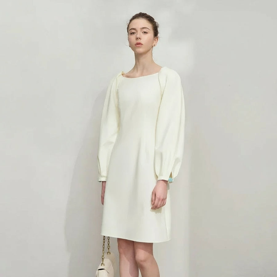 Woman wearing a white dress with long sleeves on a plain background, featuring the brand 'Amii'.