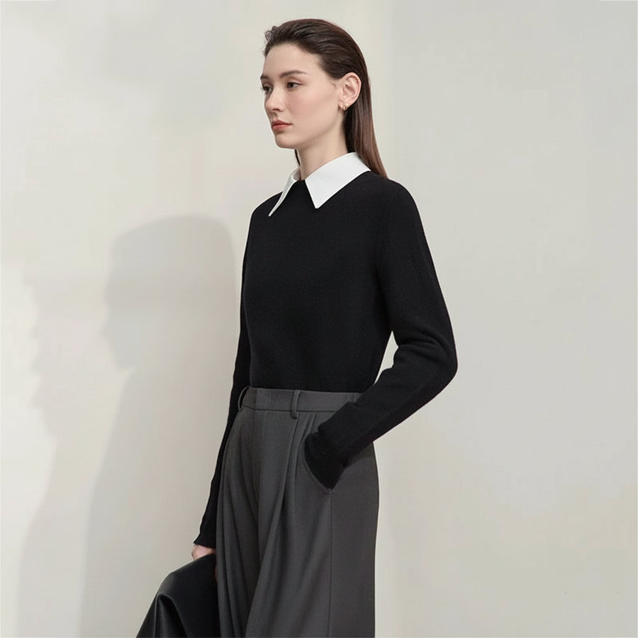 Woman wearing a black sweater with a white collar and gray pants on a plain background, featuring the AMII brand.