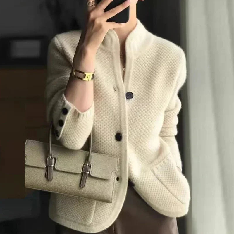 Person wearing a cream-colored cardigan holding a matching handbag.