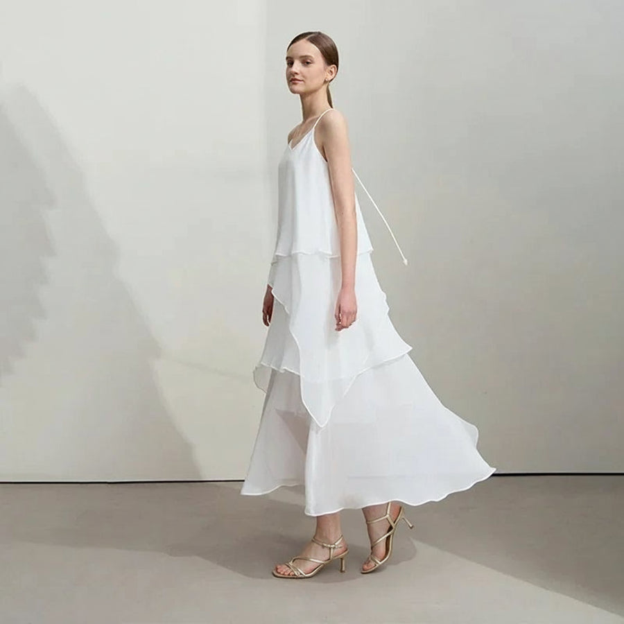 Woman wearing a white dress with a plain background, featuring the brand 'Amii'.