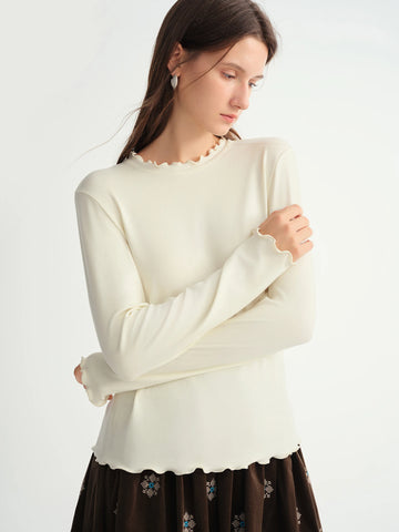 Woman wearing a white sweater with a plain background