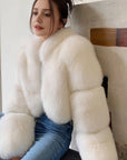 Person wearing a white fluffy coat sitting on a staircase.