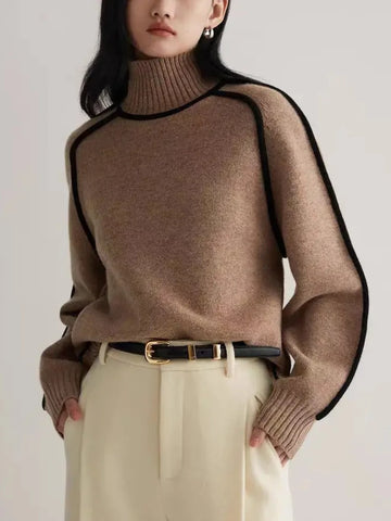 Person wearing a brown sweater with black trim against a plain background