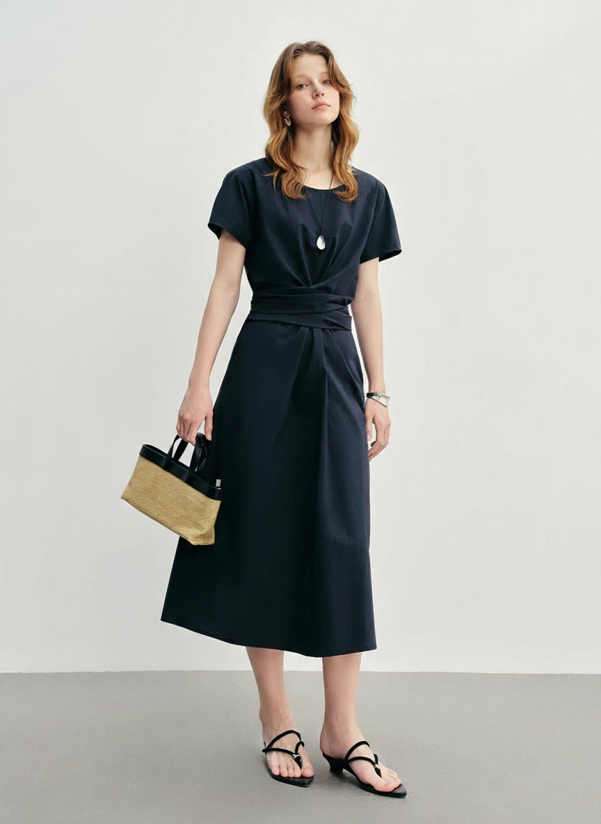 Woman wearing a black dress holding a straw bag on a plain background with 'DUSHU' branding.