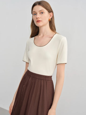 Woman wearing a white top and brown skirt on a light gray background