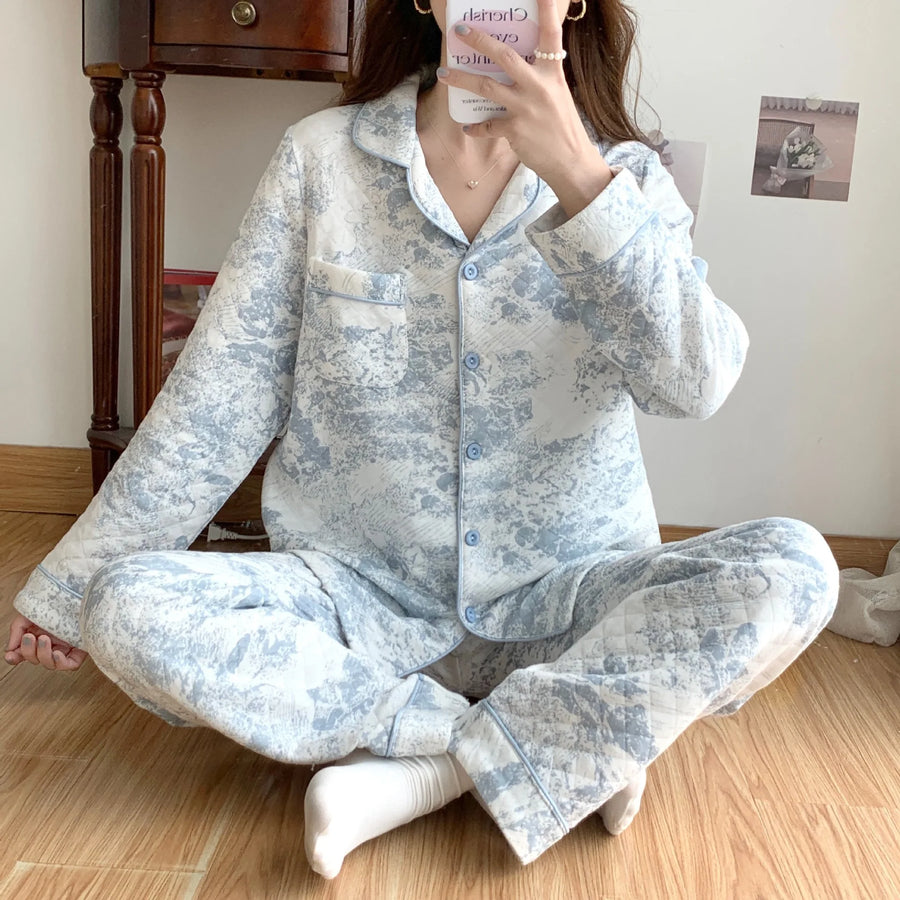 Person wearing a light blue floral pajama set sitting on a wooden floor.