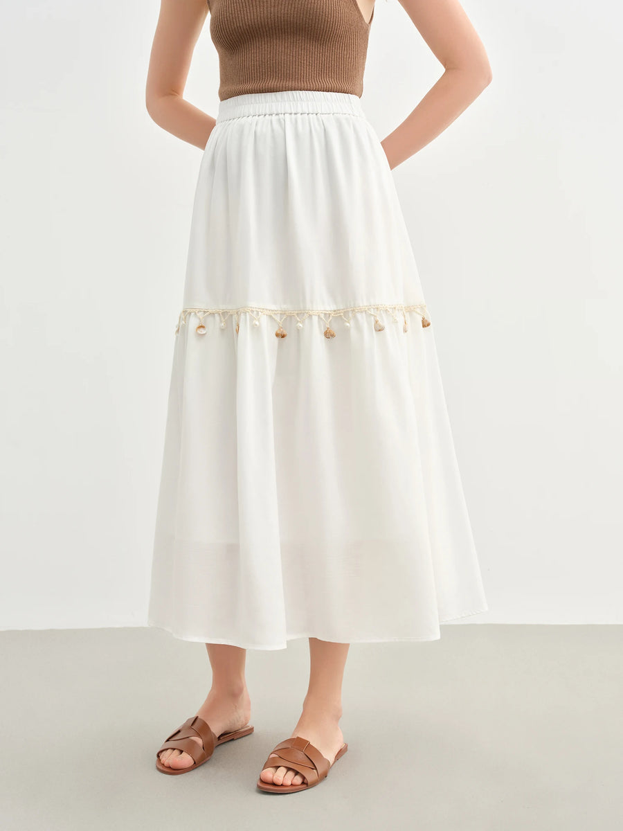 Person wearing a white skirt with decorative trim on a plain background