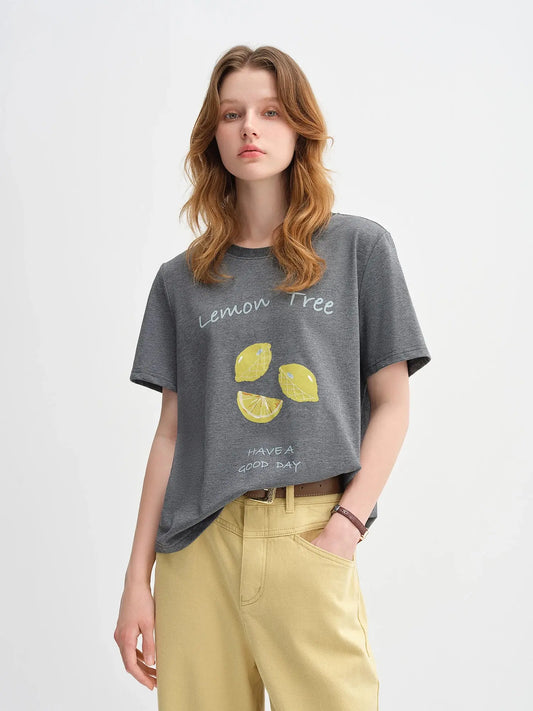 Woman wearing a gray t-shirt with lemon tree design on a plain background