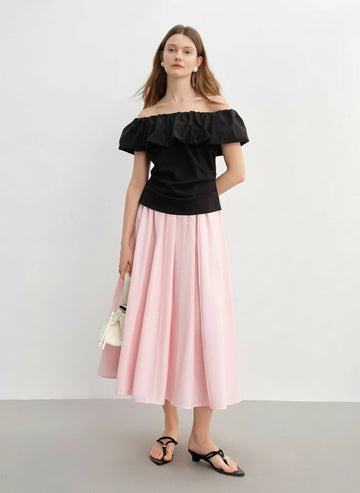 Woman wearing a black off-shoulder top and pink skirt with a white background