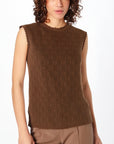 Woman wearing a brown sleeveless top with a pattern on a white background