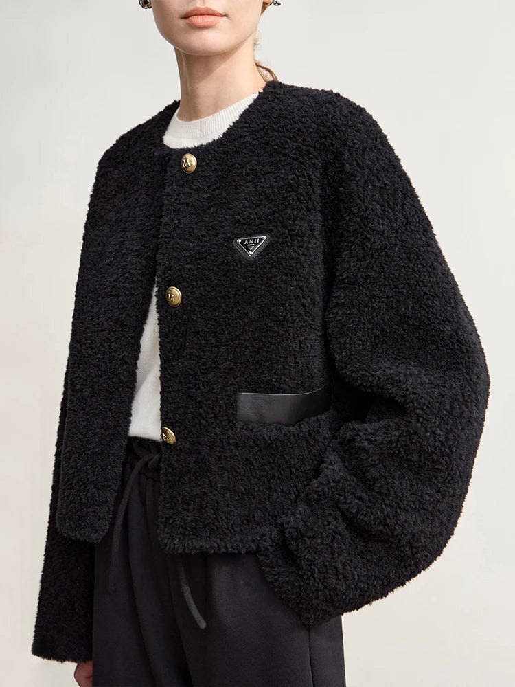 Black textured cardigan with gold buttons worn by a person on a light gray background