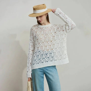 Woman wearing a lace sweater and straw hat with a plain background