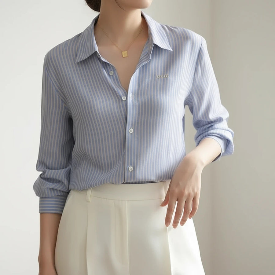 Person wearing a blue and white striped shirt with a gold necklace.