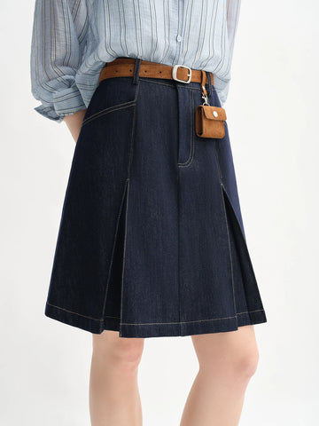 Person wearing a blue denim skirt with a brown belt and small brown bag on a white background