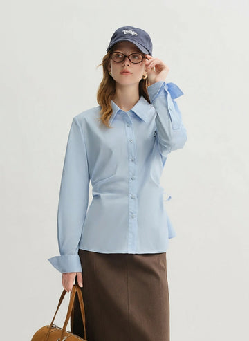 Woman wearing a light blue shirt and brown skirt with a white background, featuring the brand 'DUSHU'.