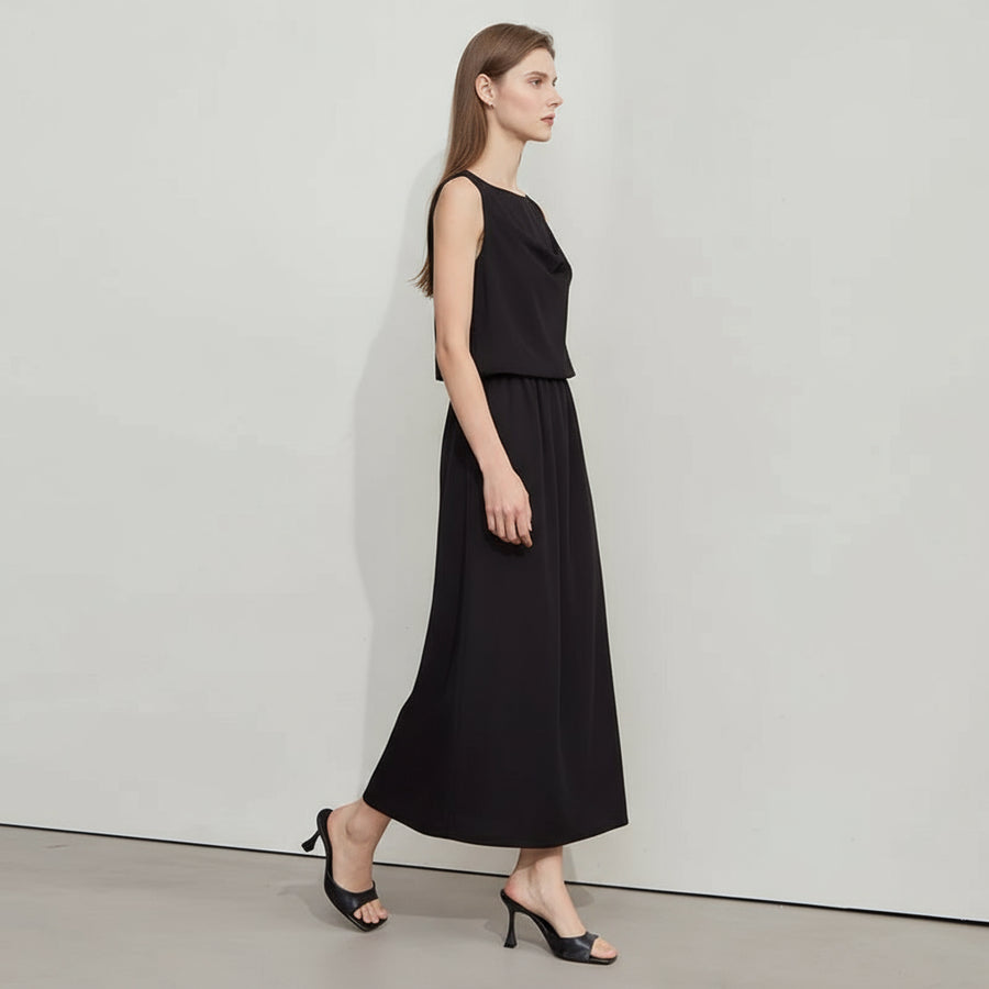 Woman wearing a black dress with a plain background, featuring the brand 'Amii'.