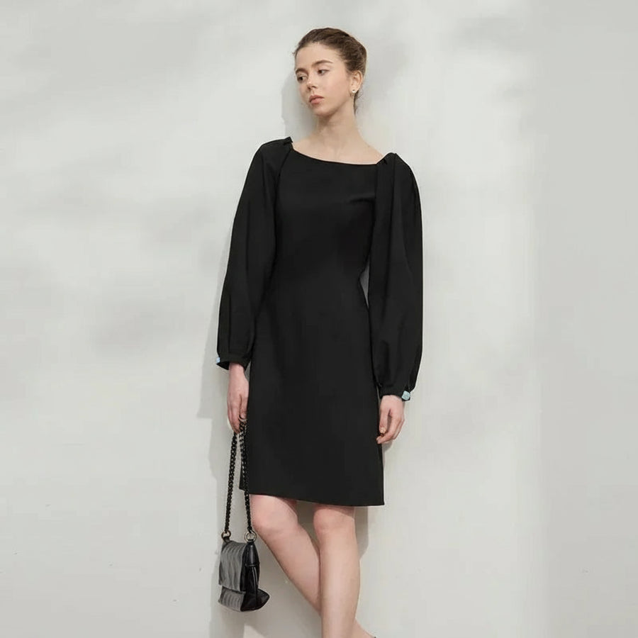 Woman wearing a black dress with balloon sleeves against a plain background, featuring the brand 'Amii'.