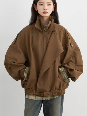 Person wearing a brown jacket with plaid accents on a white background