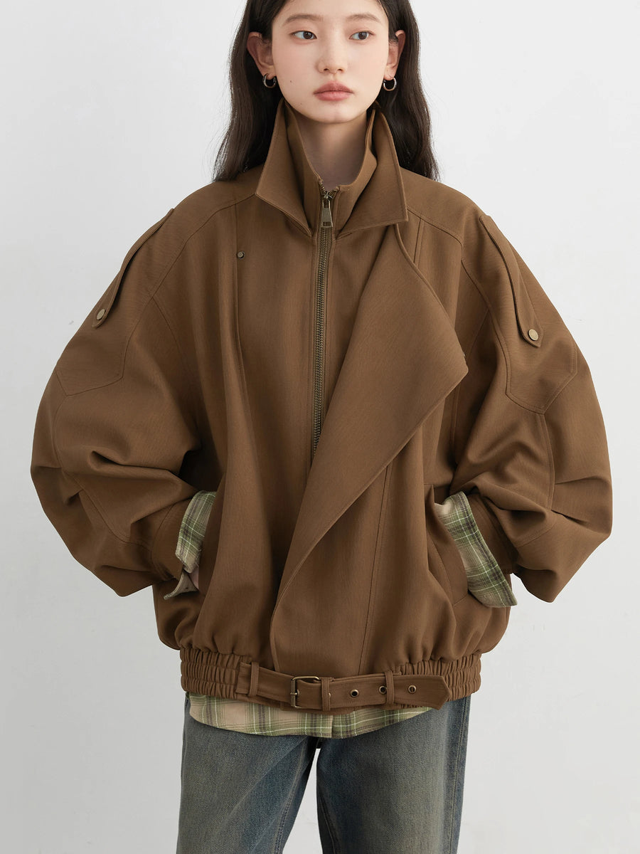 Person wearing a brown jacket with plaid accents on a white background